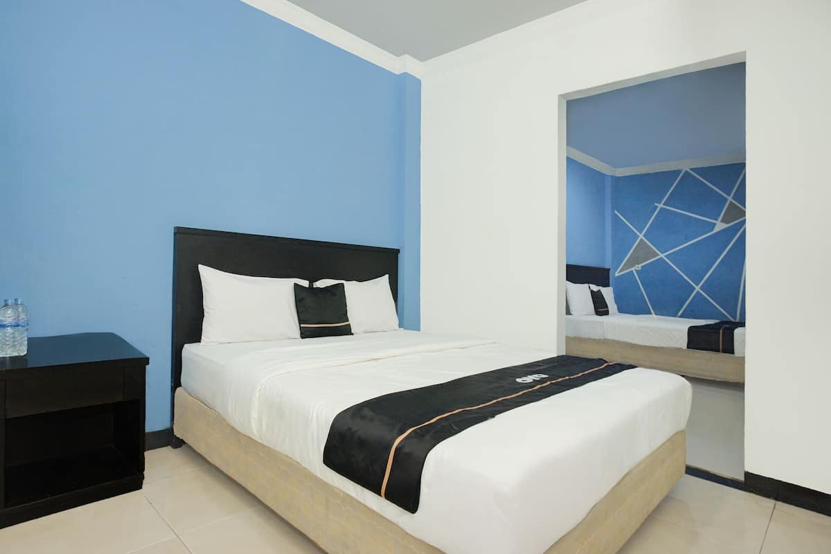 Quarto de hotel com cama, mesa de cabeceira e espelho.