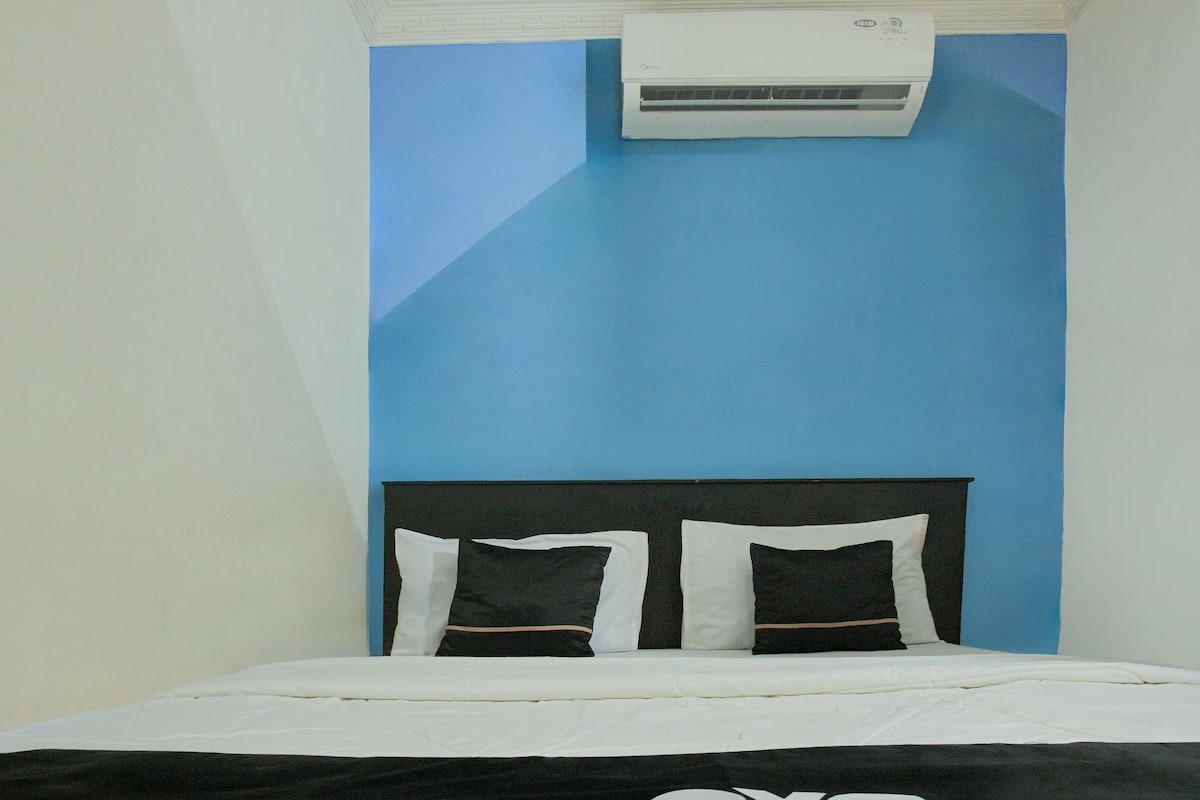 Quarto com cama, cabeceira e ar condicionado fixado na parede.