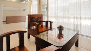 Un comedor con una mesa de vidrio, sillas de madera y un banco.