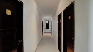 Un pasillo estrecho y bien iluminado con puertas a ambos lados, que conduce a habitaciones.