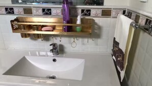 Une salle de bain avec un lavabo blanc, une commode dorée et un miroir au-dessus.