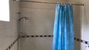 Une salle de bain avec une douche, une baignoire et une fenêtre.