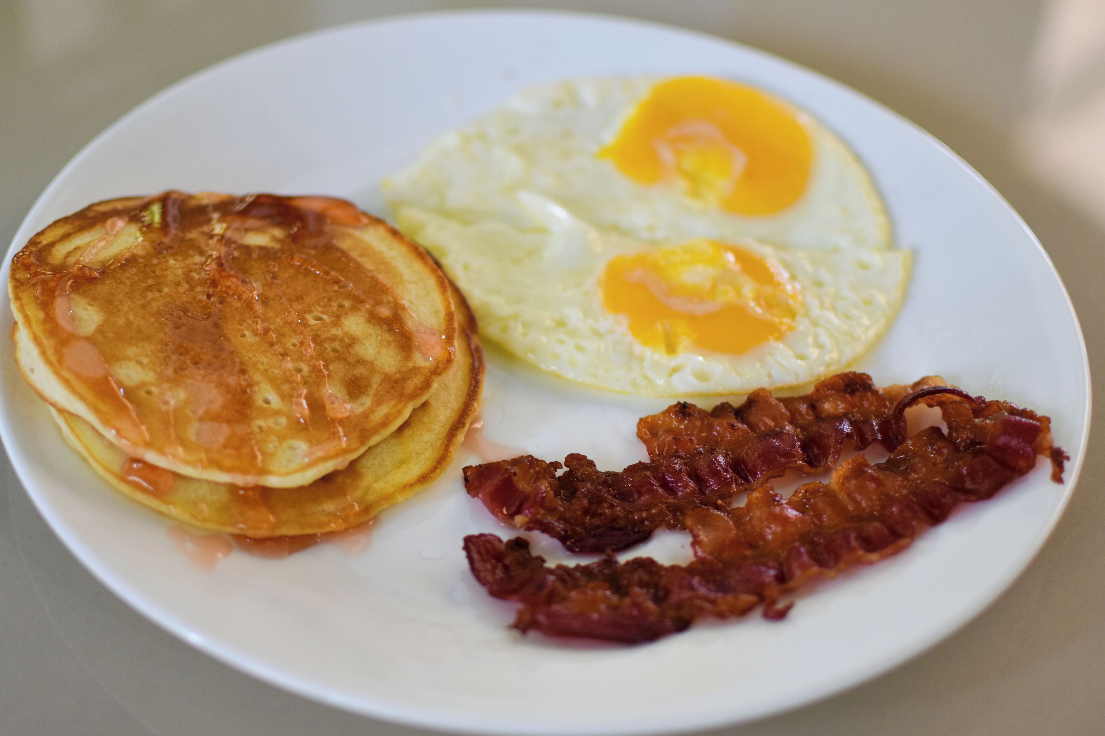 A plate with pancakes, two fried eggs, and bacon.