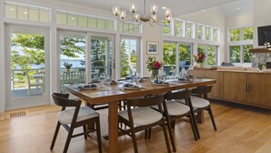 A spacious dining area with a large wooden table set for six, surrounded by chairs. - Ocean Point Boothbay Luxury Home|5BR |4.5BA|Sleeps 12 (Boothbay)