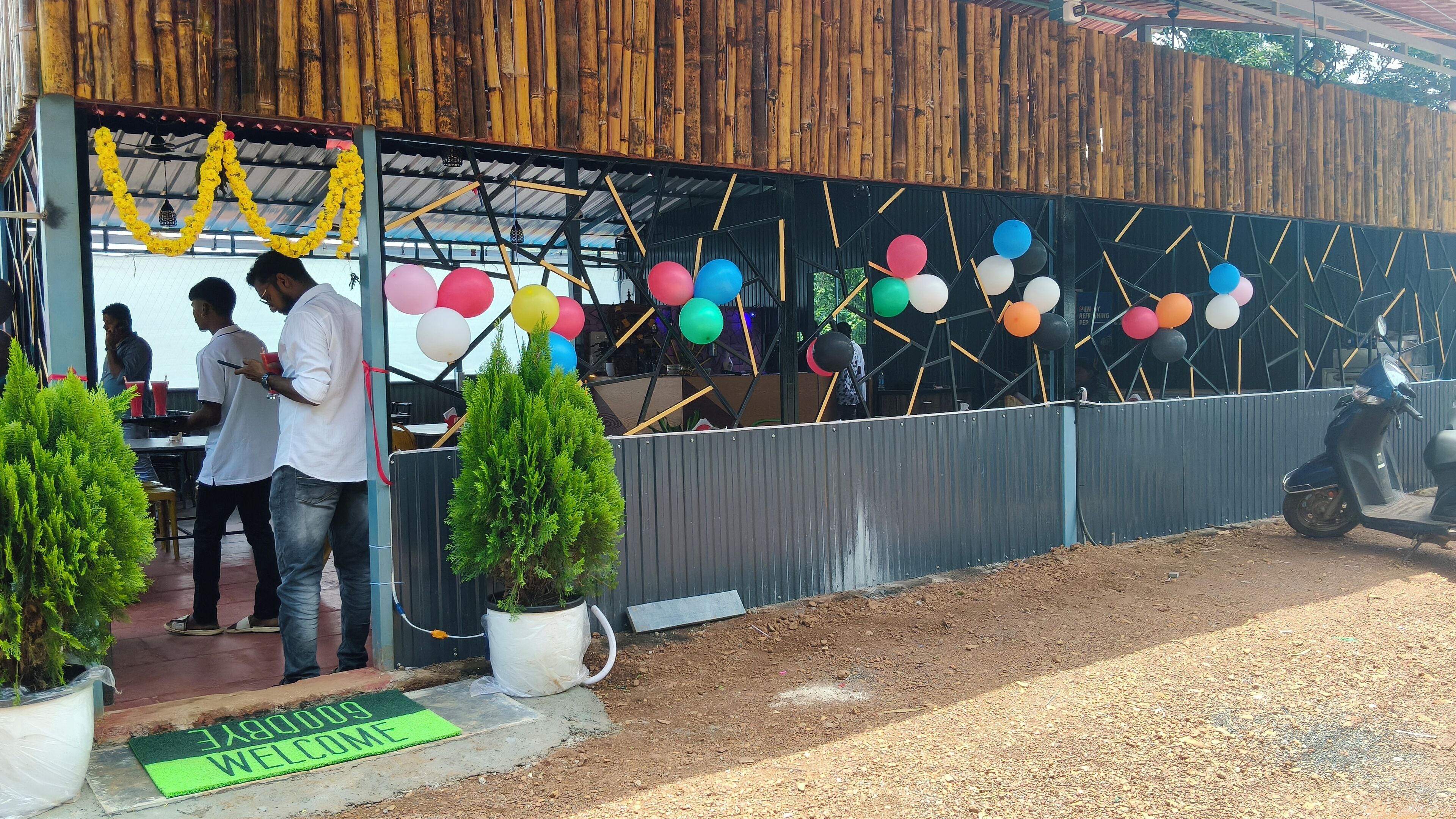 Un espace extérieur abrité, doté d’un mur en bambou, d’un toit en métal et d’une rangée de ballons colorés.