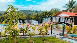 Un espace piscine avec une porte bleue, entouré de verdure et offrant une vue sur des collines en arrière-plan.