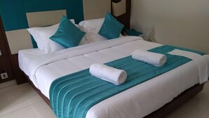 Un lit bien fait, avec une literie blanche et turquoise, un plaid turquoise et deux serviettes enroulées.