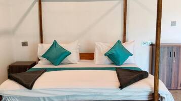 Una cama con dosel, con almohadillas blancas y turquesa, un cabecero de madera y una mesita de noche con lámpara.
