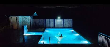 A swimming pool at night with lights.