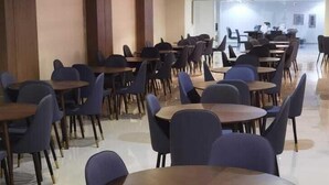 A spacious dining area with multiple round tables and chairs, featuring a clean, modern design with light-colored walls and a tiled floor. - Bilal hotel  (Makkah)