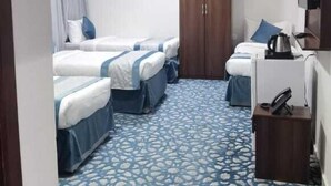 A hotel room with two beds, a wardrobe, a desk with a kettle, and a patterned carpet. - Bilal hotel  (Makkah)