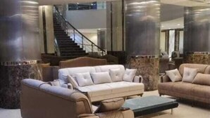 A spacious lobby with a beige sofa set, a coffee table, and a staircase in the background. - Bilal hotel  (Makkah)