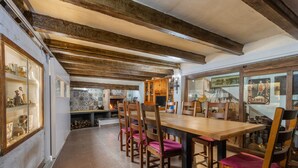 Un coin repas avec une table et des chaises en bois, une cheminée et un mur recouvert de carreaux décoratifs.