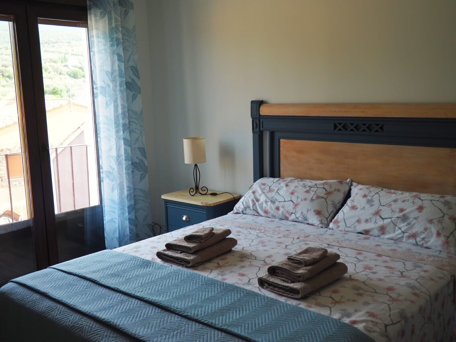 Une chambre d’hôtel avec un lit, une table de chevet, une lampe et une vue sur l’extérieur.