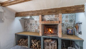 Une cuisine traditionnelle avec un poêle à bois, un dosseret carrelé et un four en briques.