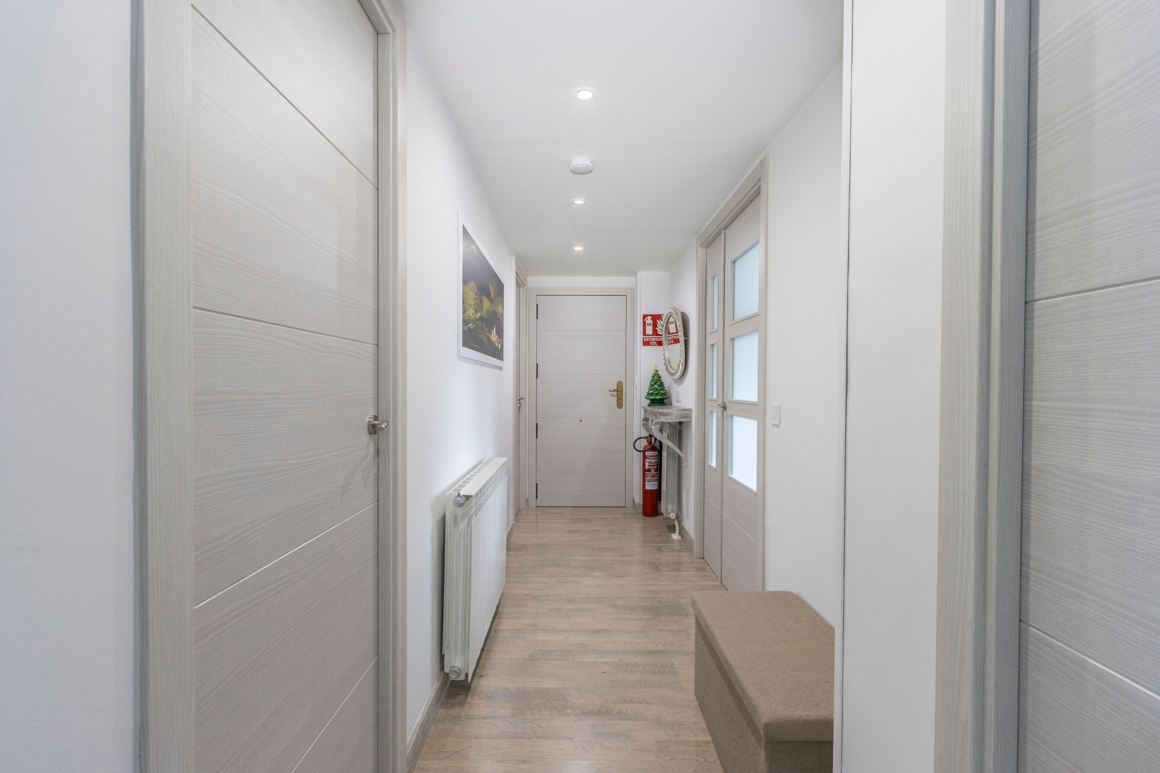 A hallway with a radiator, a fire extinguisher, and a bench.