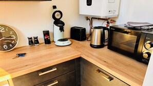 A compact kitchen with a coffee maker, kettle, microwave, and a clock. - Le Ronsard, Chinon View of the fortress & Collegiate church of Saint Mexme - Historic center 5mn (Chinon)