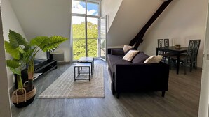 A modern loft bedroom with a large skylight, a dark sofa, a dining table, and a potted plant. - Le Ronsard, Chinon View of the fortress & Collegiate church of Saint Mexme - Historic center 5mn (Chinon)