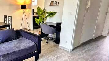 Moderni olohuone, jossa on sohva, sohvapöytä ja lamppu. Huoneessa on myös ruokailutila, jossa on pöytä ja tuolit. Huoneesta on näkymä sisäpihalle.
