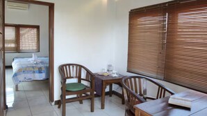 A room with a bed, a table with chairs, and a window with blinds. - The Studio at Warung Bambu Pemaron (Buleleng)