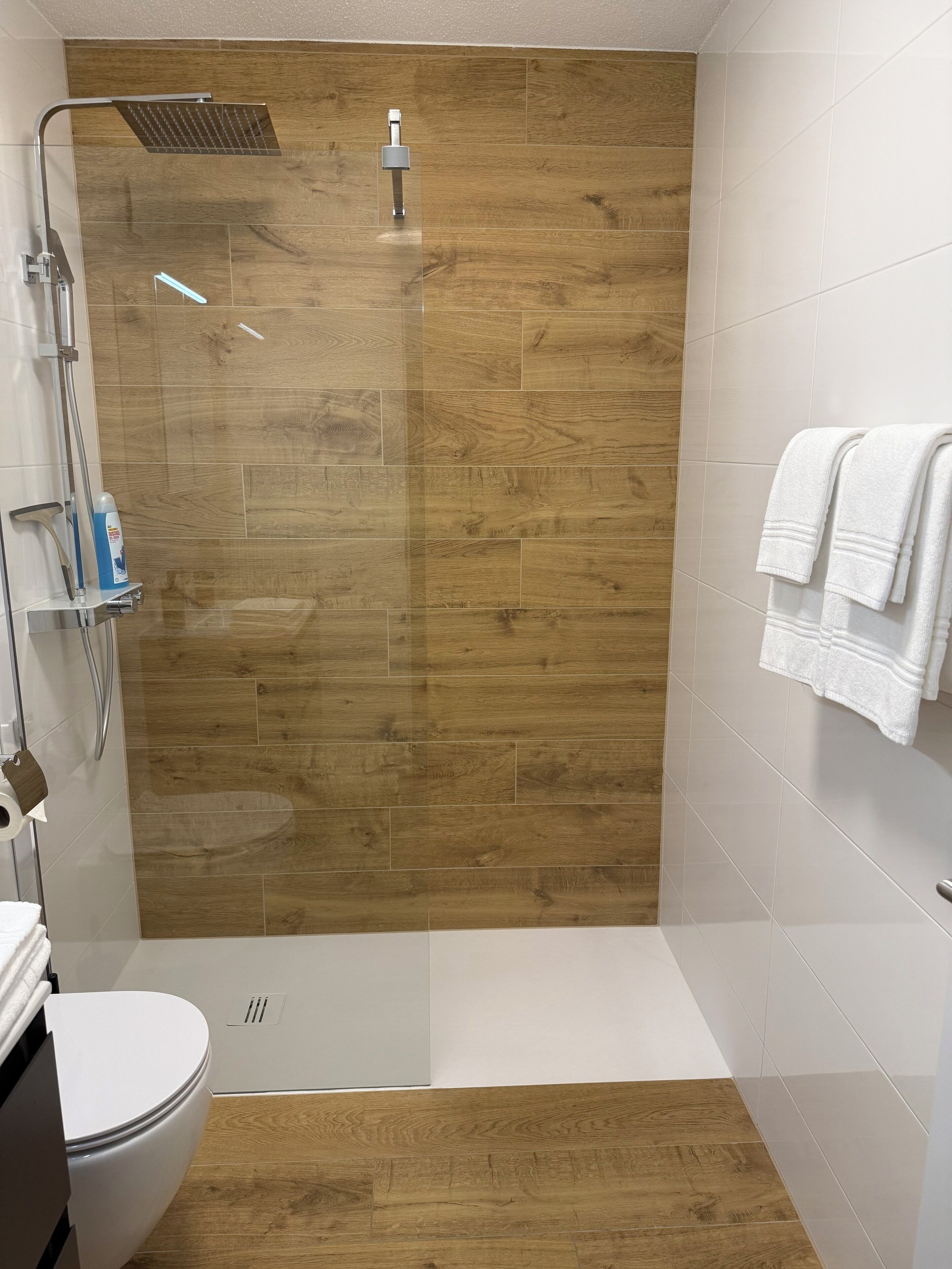 A modern bathroom with a shower, toilet, and a towel rack.