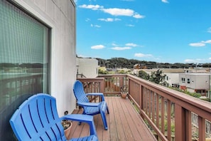 A balcony with two blue chairs and a potted plant.