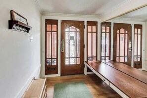 Une pièce avec un long banc en bois, un tapis vert et trois portes en bois dotées de panneaux de verre.