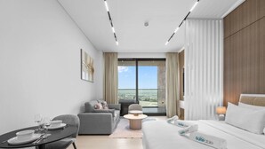 A modern hotel room with a bed, a sofa, a dining table, and a view of the city. - Mesmerizing Canal View Studio with private Jacuzzi (Dubai)