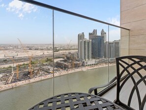 A balcony with a view of a river, construction cranes, and high-rise buildings. - Mesmerizing Canal View Studio with private Jacuzzi (Dubai)