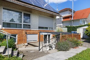 Une maison d’habitation avec un garage, un patio couvert et un toit équipé de panneaux solaires.