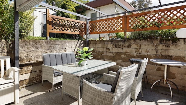 An outdoor patio with wicker furniture, a table, and a chair.