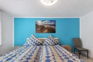 Une chambre à coucher avec un lit, deux oreillers, une table de chevet, une chaise et un tableau accroché au mur.