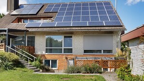 A house with solar panels, a brick facade, and a wooden deck.