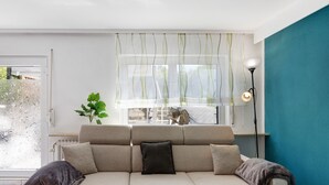 A modern living room with a sofa, a potted plant, and a lamp.