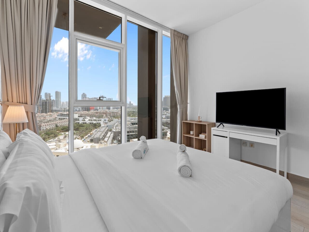 A hotel room with a large bed, a TV, and a view of the city.