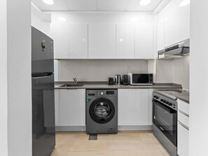 A compact kitchen with a washing machine, microwave, and oven.