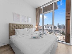 A hotel room with a large bed, a city view, and a window with curtains.