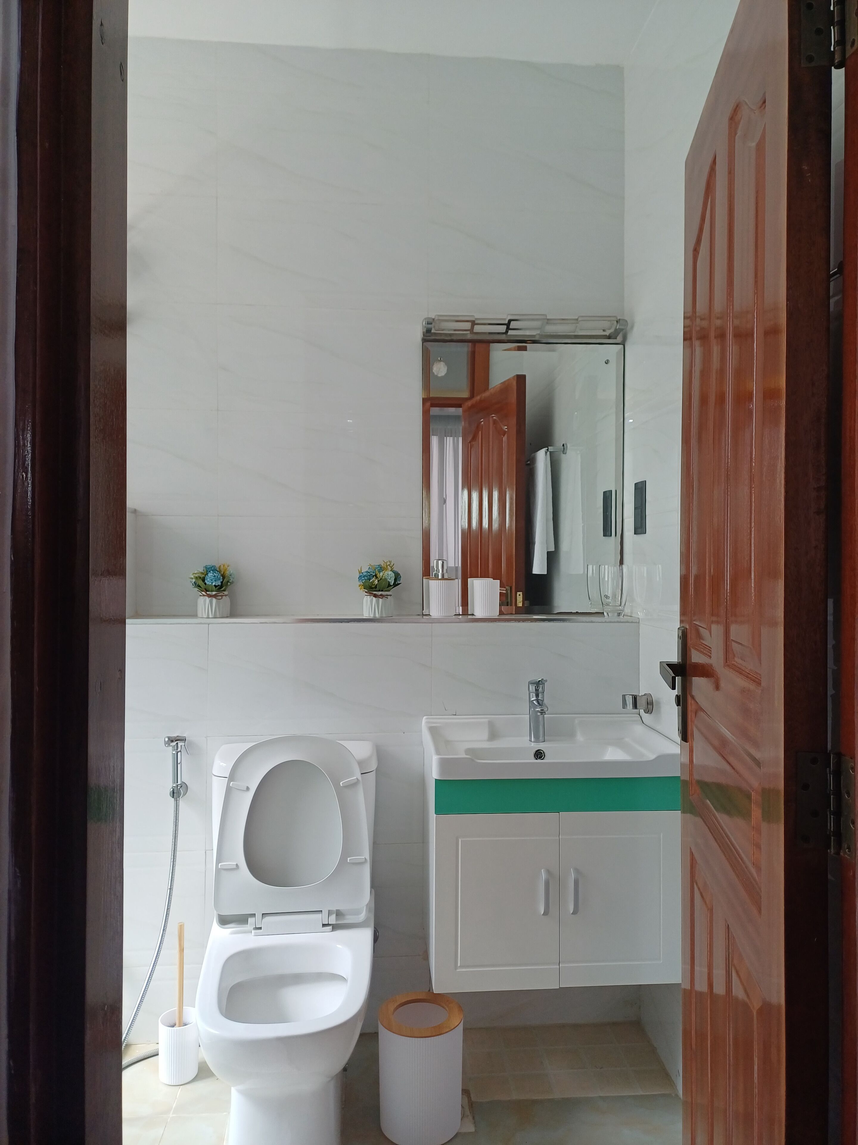 Ein Badezimmer mit Toilette, Waschbecken, Spiegel und Holztür.