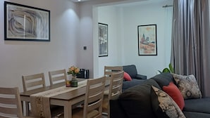 Una sala de estar moderna con comedor, sofá y una araña.