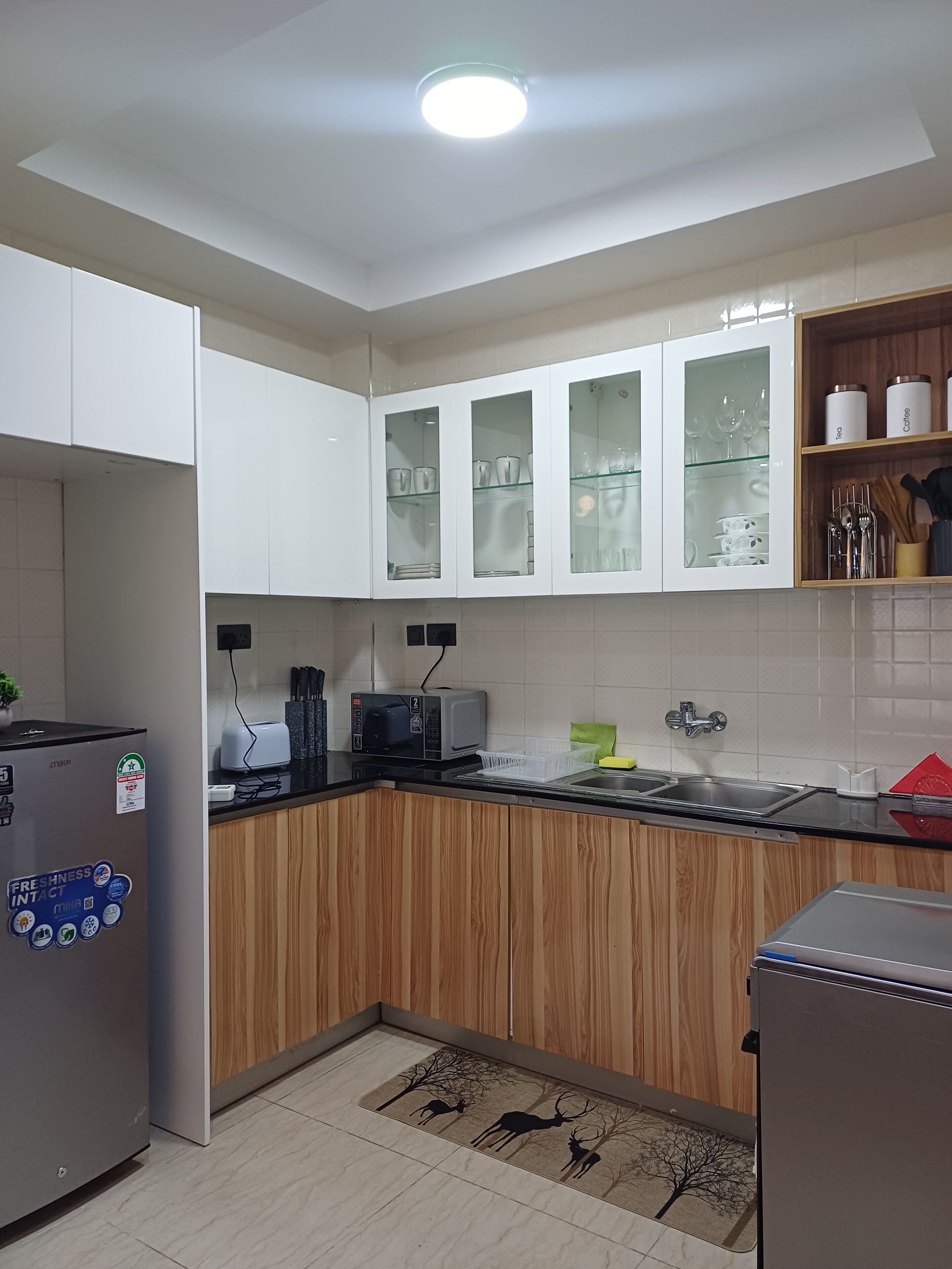 A kitchen with white cabinets, a microwave, a sink, and a refrigerator.