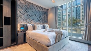 A modern bedroom with a large bed, a built-in wardrobe, a flat-screen TV, and a city view. - Unique spacious 1 BR Porsche Design Marina View (Dubai)