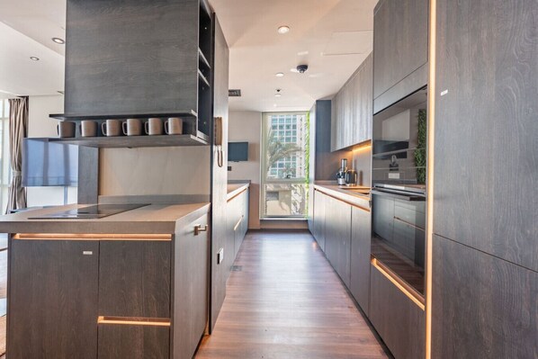 Una cocina moderna con armarios de madera oscura, una isla central y vistas al exterior.