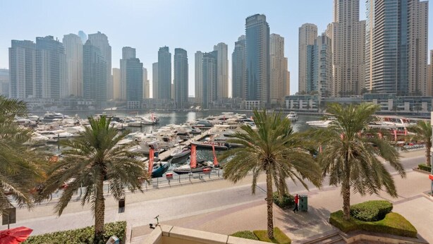 A marina with numerous boats docked, surrounded by tall residential buildings and palm trees. - Unique spacious 1 BR Porsche Design Marina View (Dubai)