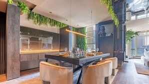 A modern dining area with a central island, cushioned seating, and a view of the kitchen. - Unique spacious 1 BR Porsche Design Marina View (Dubai)