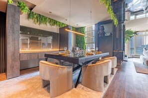 A modern dining area with a central island, cushioned seating, and a view of the kitchen.