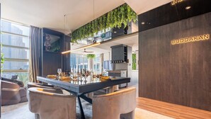 Un espace repas moderne avec un îlot central, des sièges et une cuisine en arrière-plan.