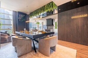 Een moderne eetruimte met een centraal eiland, zitplaatsen en een keuken op de achtergrond.