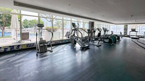 Une salle de sport équipée de machines de cardio, dotée de grandes fenêtres et offrant une vue sur l’extérieur.