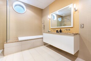 A modern bathroom with a bathtub, a large mirror, and a vanity with a sink.
