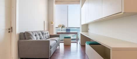 Ein modernes, kompaktes Wohnzimmer mit Sofa, kleinem Tisch und Blick ins Freie.